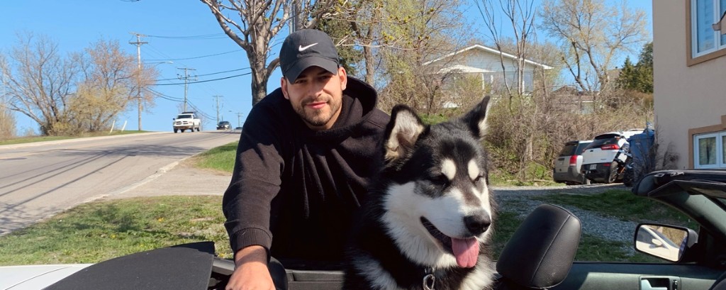 Membre de l’équipe Fab Paws avec un grand chien noir et blanc heureux dans une décapotable par une journée ensoleillée.